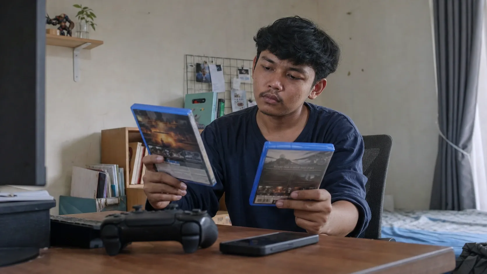 Seorang pemain membandingkan pilihan game di meja belajarnya sebelum bermain