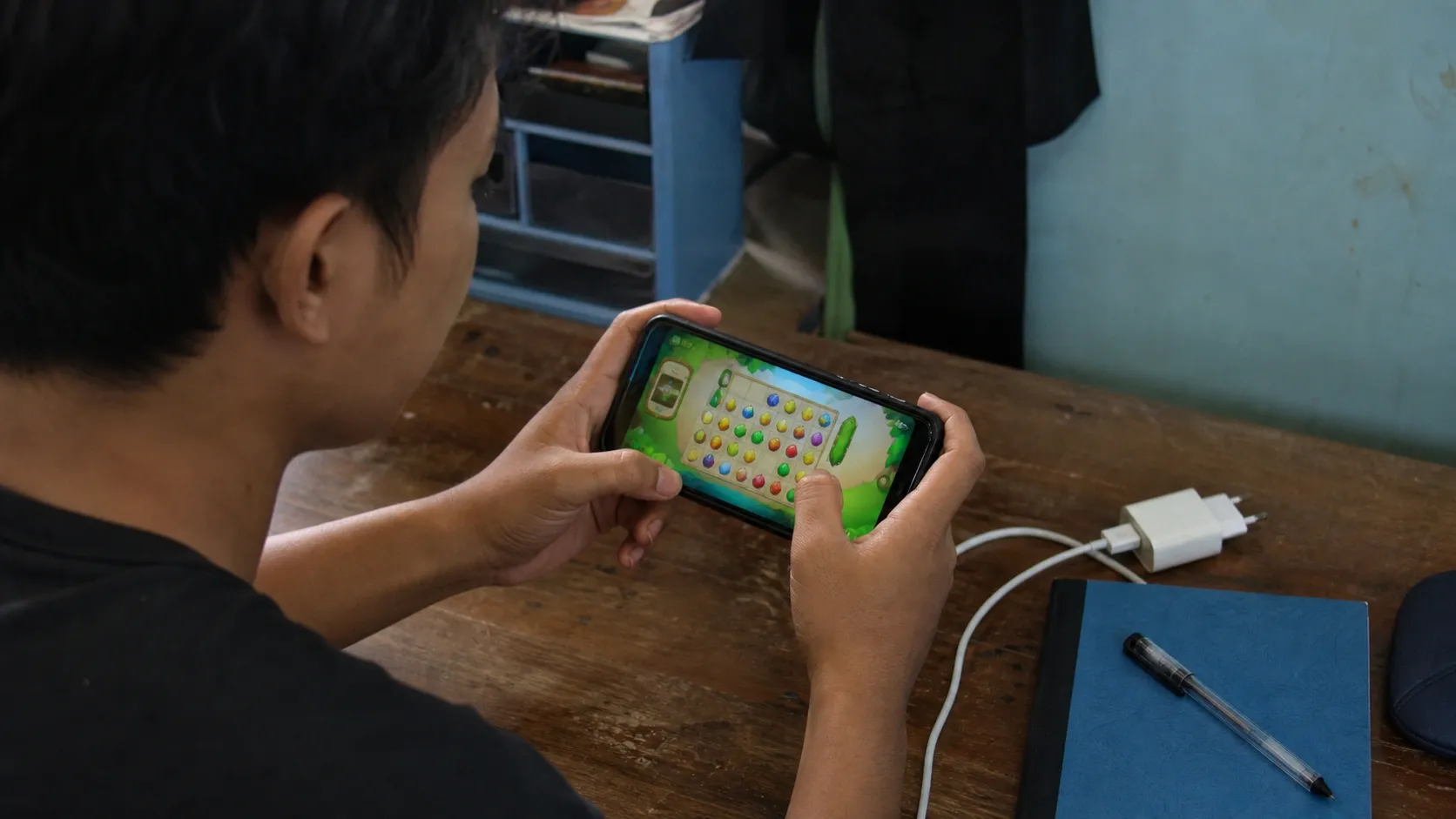 Ponsel Android sederhana dengan casing usang digunakan bermain game ringan di meja