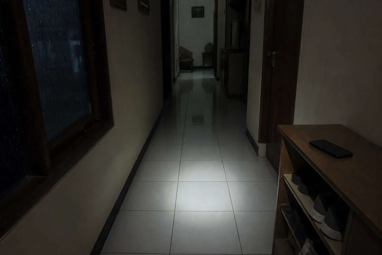 Koridor rumah redup saat hujan sebagai suasana game horror mobile yang bikin merinding