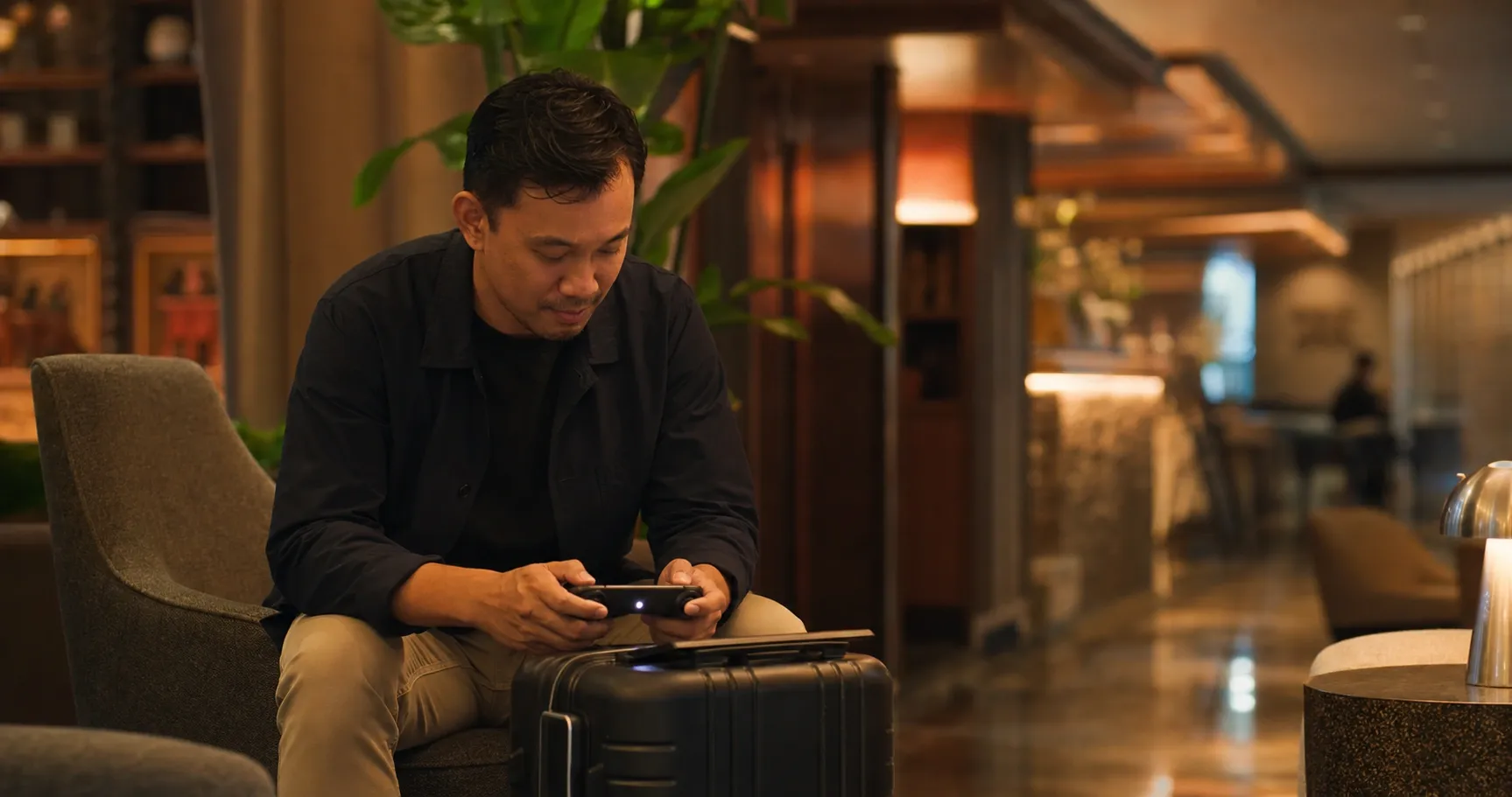 Controller ringkas dan ponsel di atas koper sebagai gambaran main game PC di HP dengan remote play